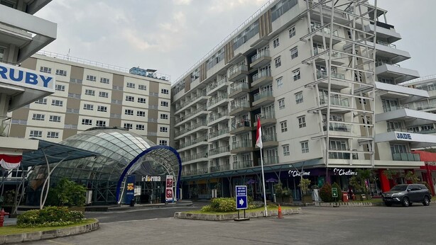 Ein mehrstöckiges Hotel mit modernem architektonischen Design, das Balkone und einen auffälligen Glaseingang bietet.