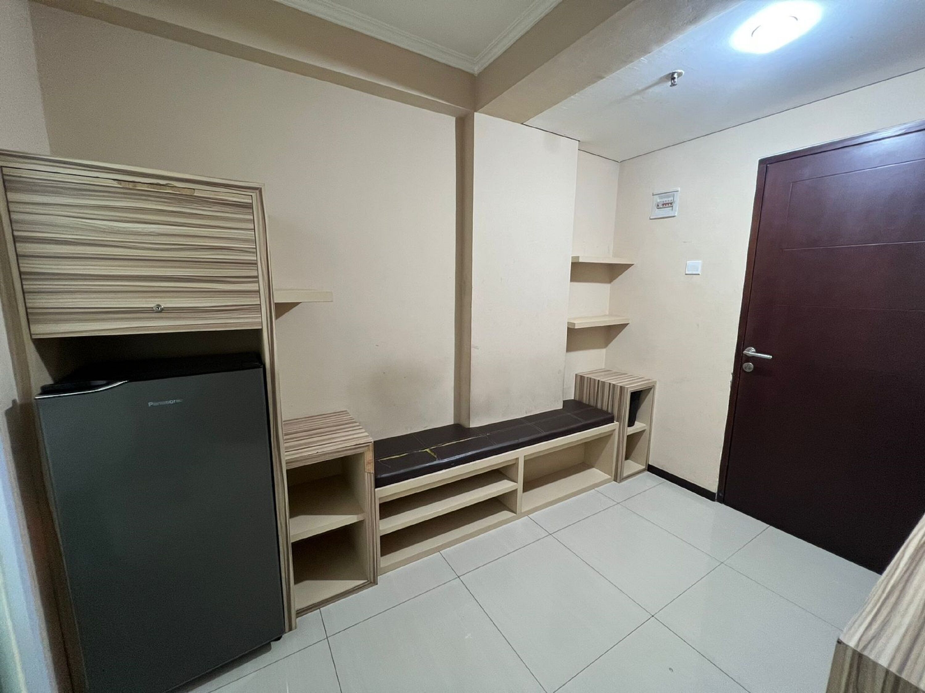 Ein kleines Zimmer mit eingebautem Kühlschrank, einer Sitzbank und einer Tür.