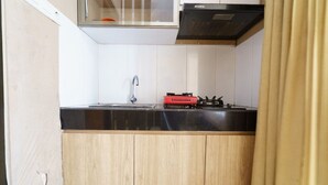 Eine kleine Küche mit schwarzem Arbeitsplatz, einer Edelstahl-Spüle und einem roten Gasherd.