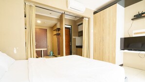 Ein Hotelzimmer mit einem großen Bett, einem an der Wand montierten Fernseher und einer Schiebetür zu einem Badezimmer.