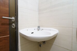 Une salle de bain avec un lavabo blanc, une porte en bois et des murs carrelés.