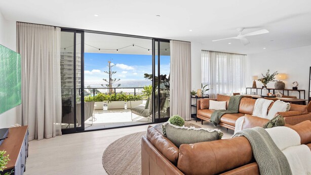 A modern living room with a leather sofa, a round rug, and a view of the outdoors through large sliding glass doors. - Welcome to your seaside sanctuary at Magnoli Palm Beach! (Gold Coast)