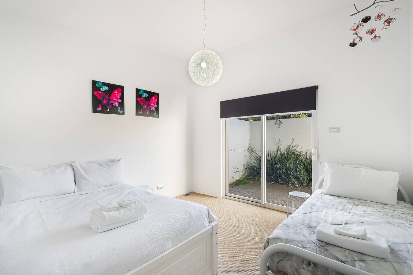 Une chambre avec deux lits, une grande fenêtre et une vue sur un jardin.