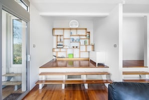 Un salon moderne avec un banc en bois, un canapé blanc et une bibliothèque intégrée.