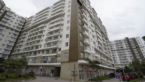 Un edificio residencial de varios pisos con balcones, entrada a nivel de calle y zona de estacionamiento.