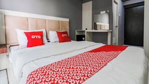 Una habitación de hotel moderna con una cama grande, un cabecero, un armario y una estantería.