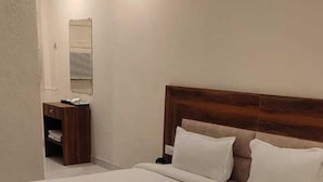 Un lit bien fait, avec une tête de lit en bois, une table de chevet et un miroir au mur.