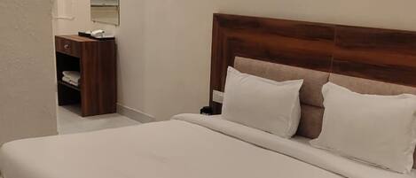 A single-bed room with a wooden headboard, a bedside table, and a nightstand.