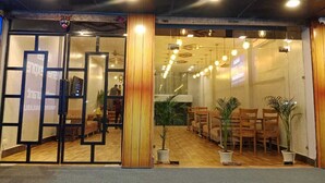 L’entrée d’un hôtel, avec un espace de réception, un plancher en bois et plusieurs plantes en pot.