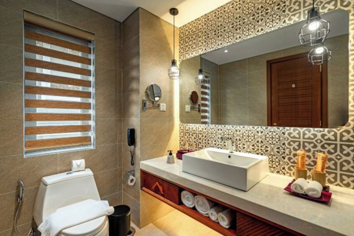 Een moderne badkamer met een grote spiegel, toilet, wastafel en handdoekhouder.