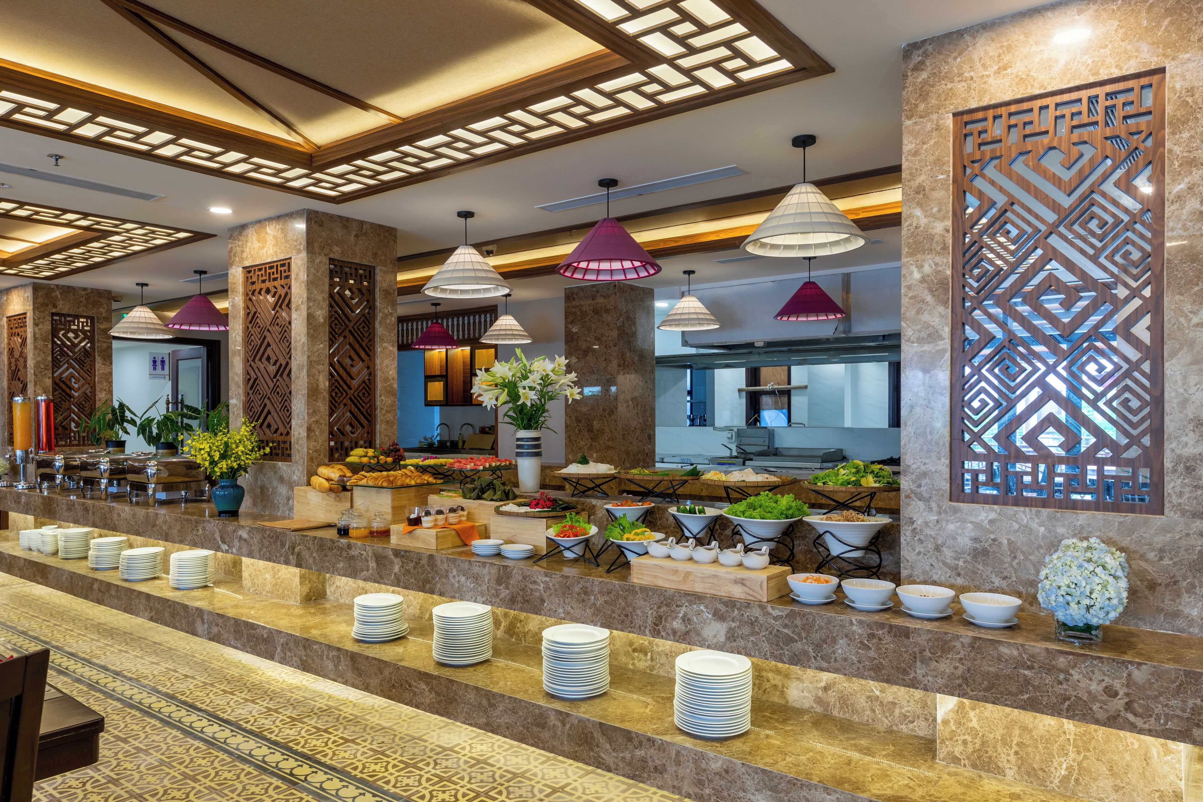 A hotel lobby with a buffet area, marble columns, and pendant lighting.