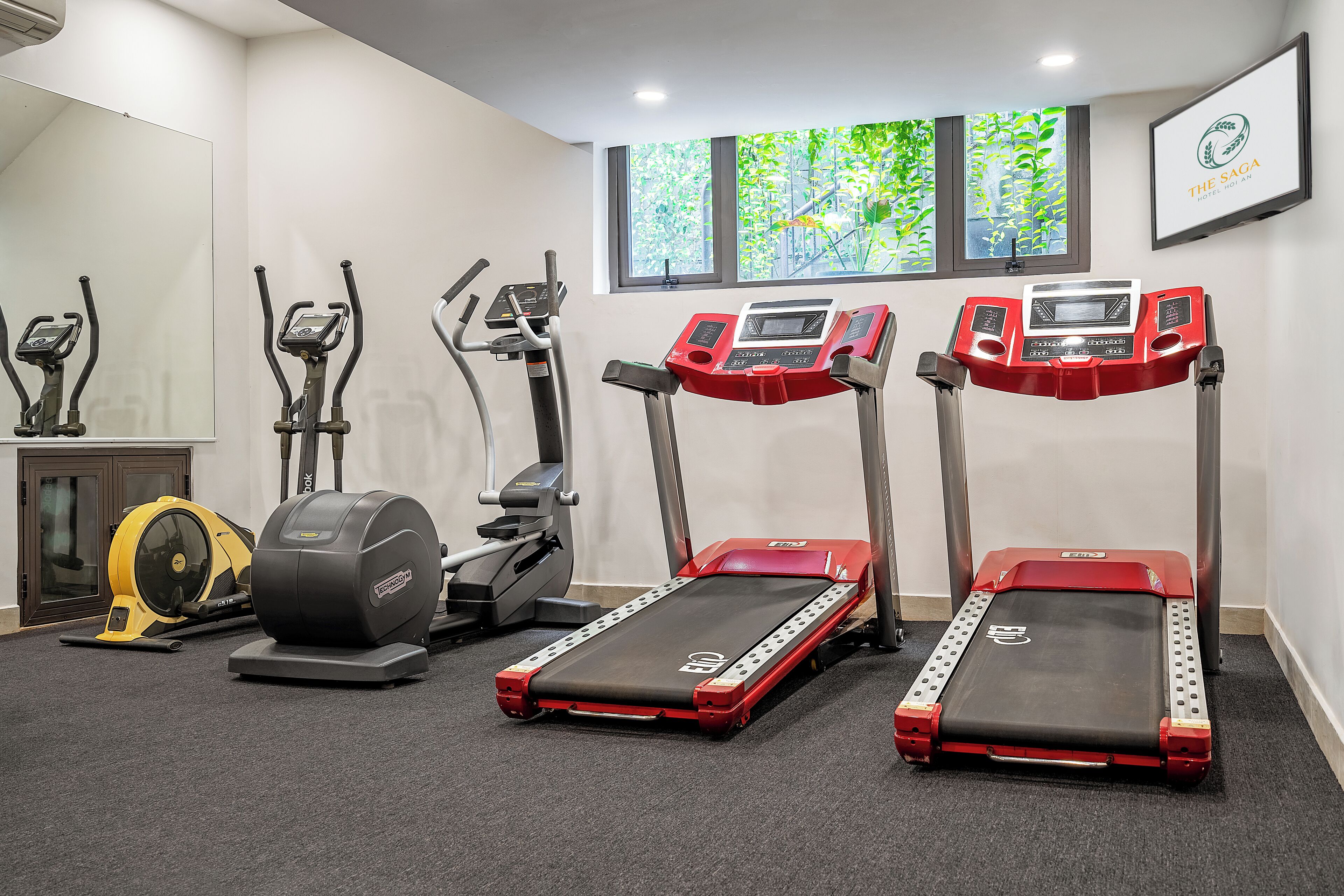 A gym with treadmills, elliptical machines, and a stationary bike.