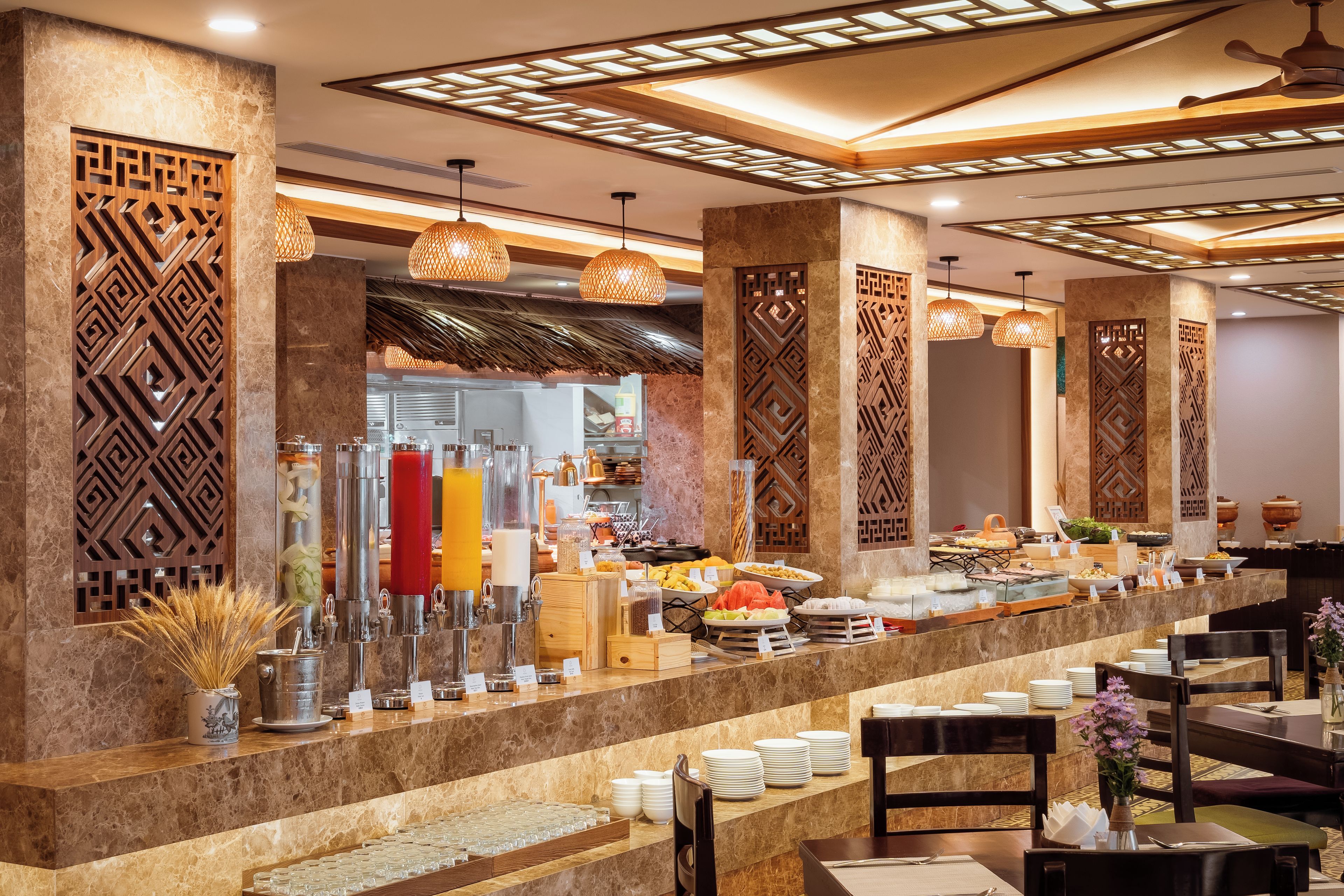 Un hall d’hôtel doté d’un espace buffet, de colonnes en marbre et de luminaires suspendus.
