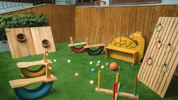 Kids can play on the basketball hoop, seesaw, and climbing wall in this outdoor play area.