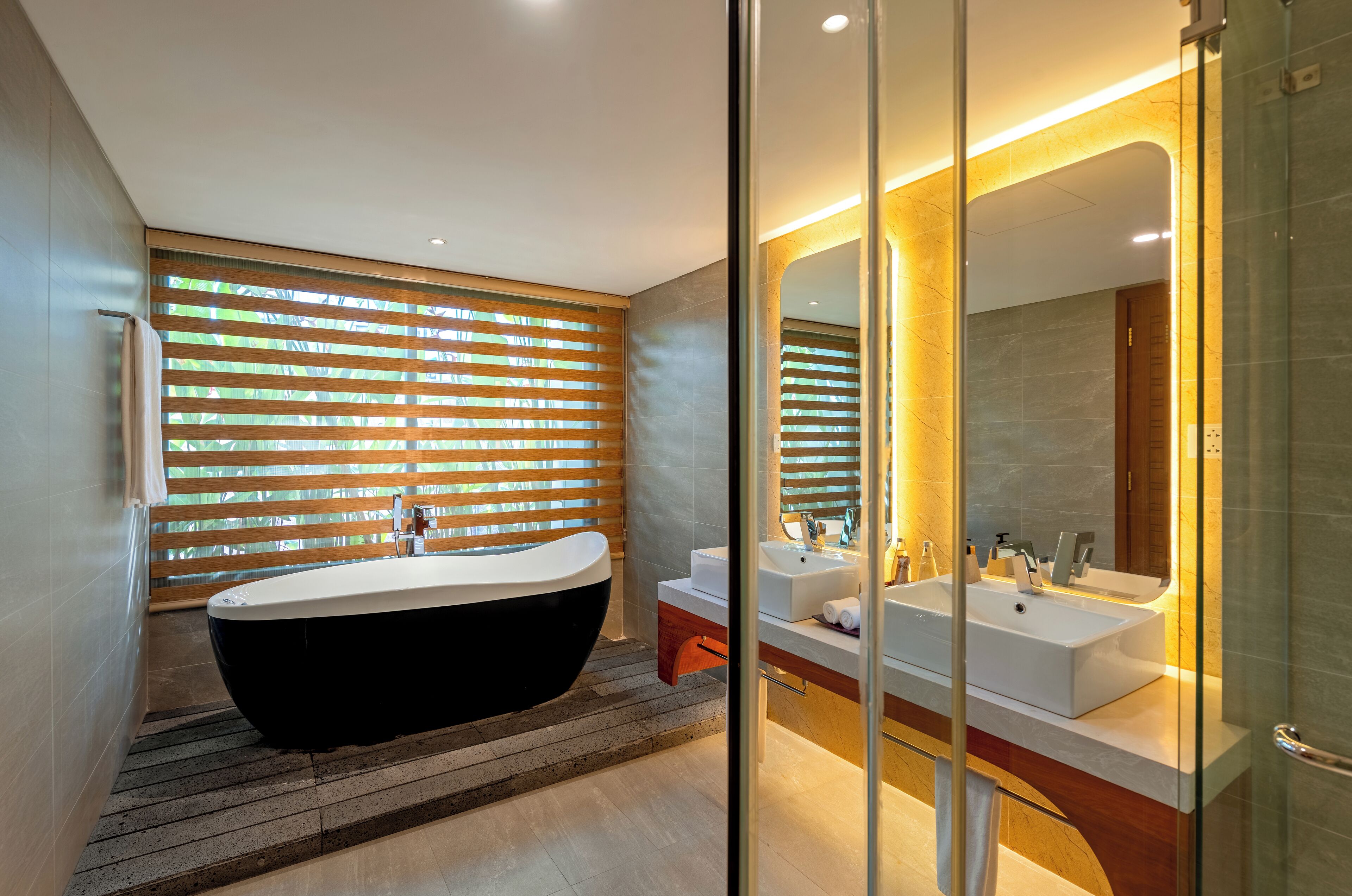 A modern bathroom with a freestanding bathtub, a glass-enclosed shower, and a vanity with a large mirror.