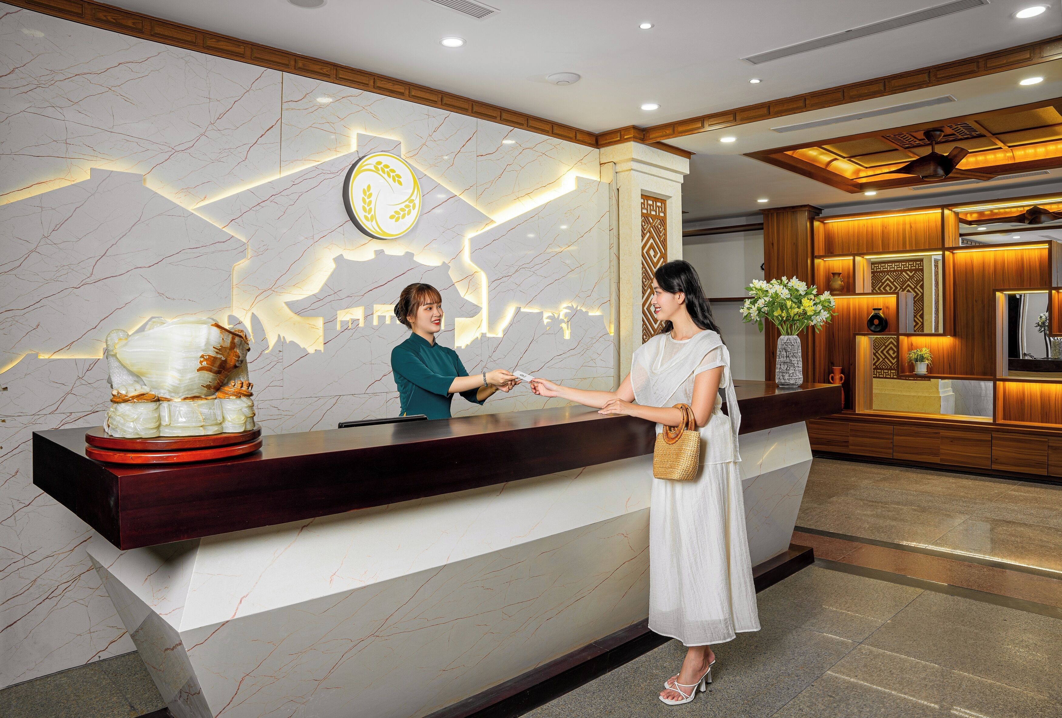A reception desk with a marble wall and a logo above it.