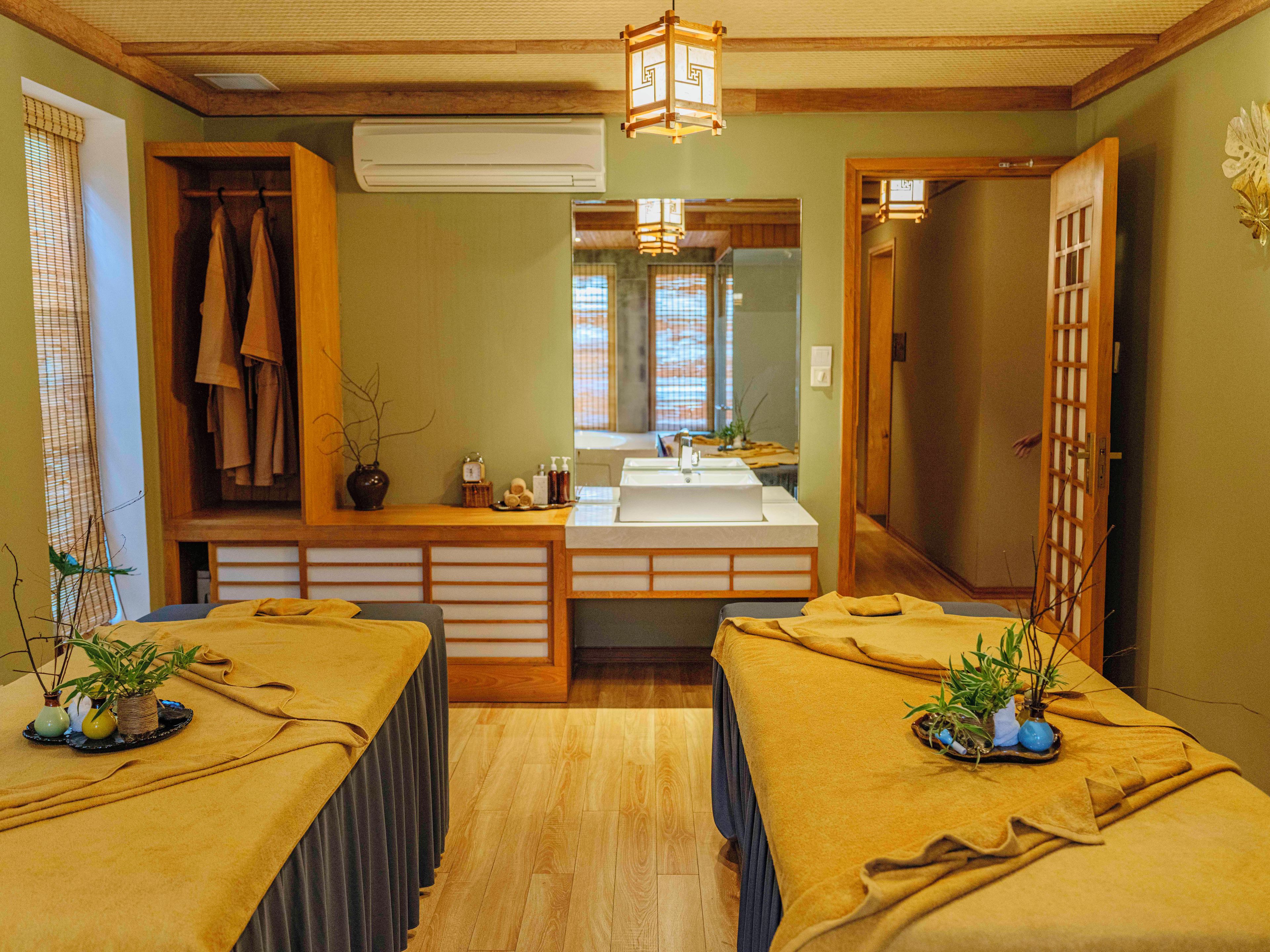 Una habitación con dos camillas de masaje, un lavamanos y un espejo.
