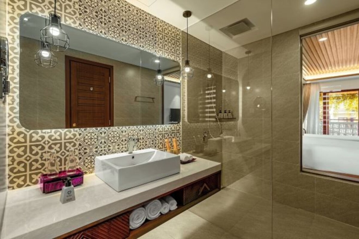 Un baño moderno con un espejo grande, un lavamanos blanco y una zona de ducha.