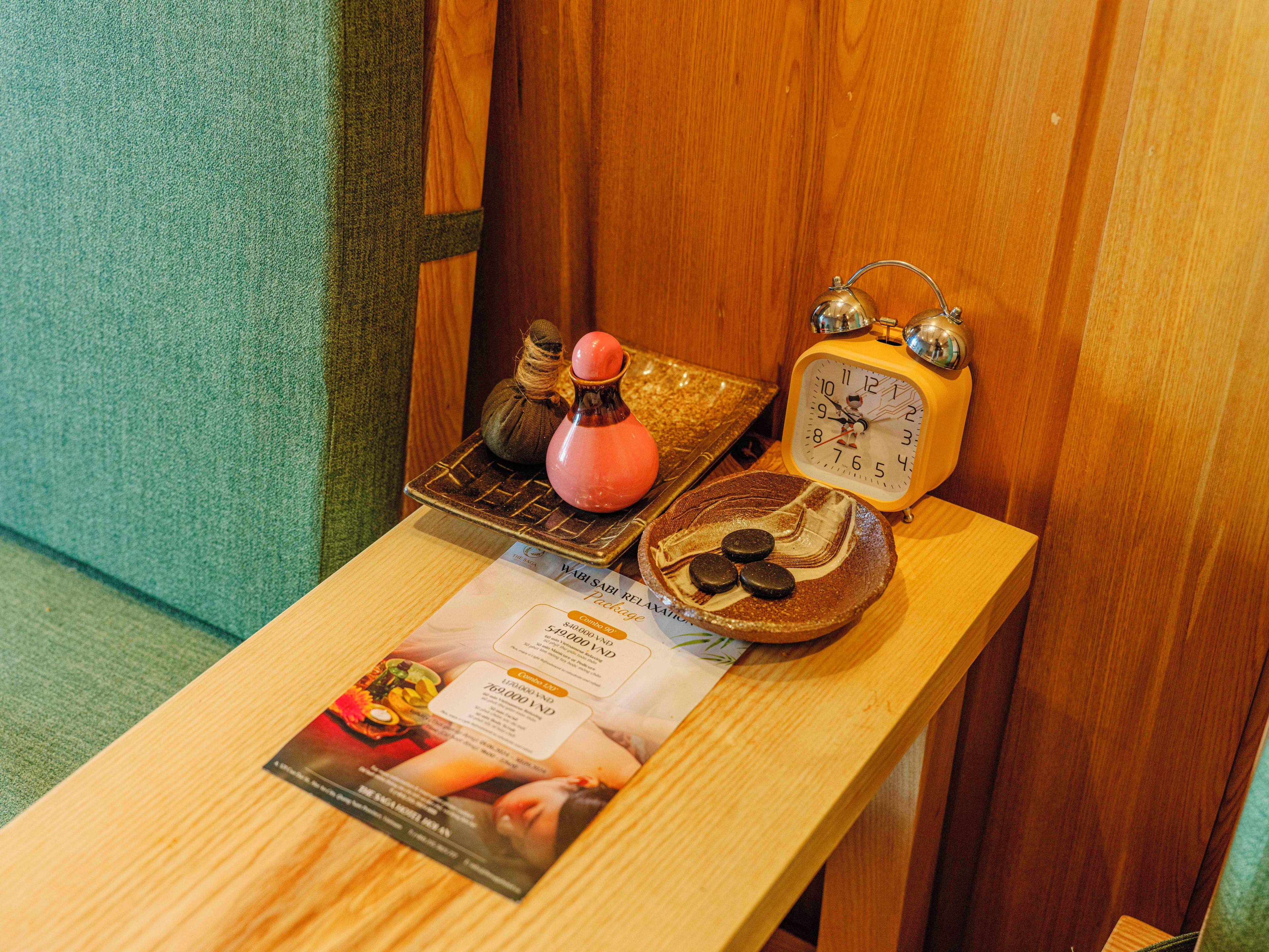 A wooden table with a ceramic clock, a decorative bowl, and a magazine.