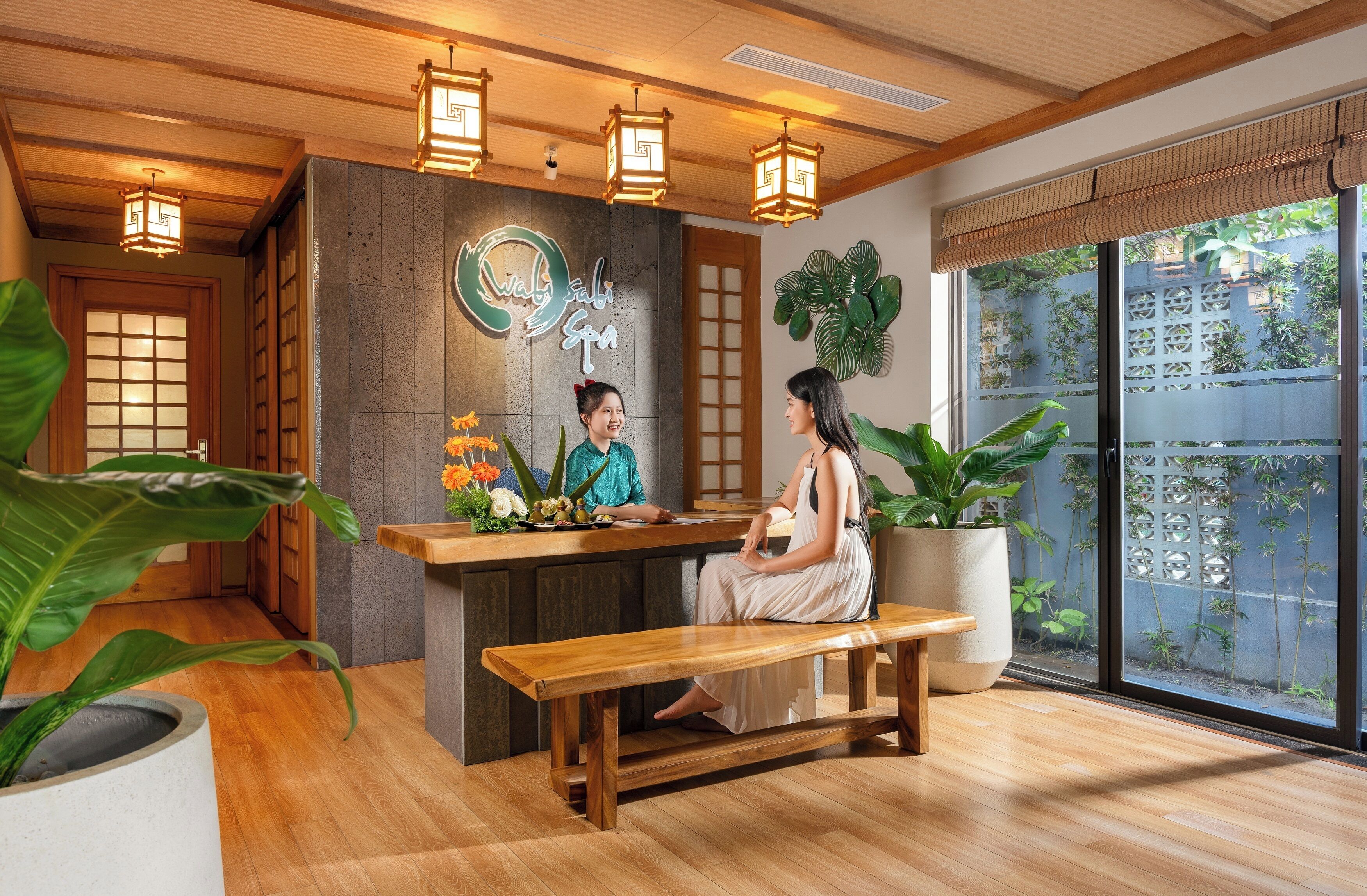 A reception area with a wooden bench, a reception desk, and a large window with a view of greenery.