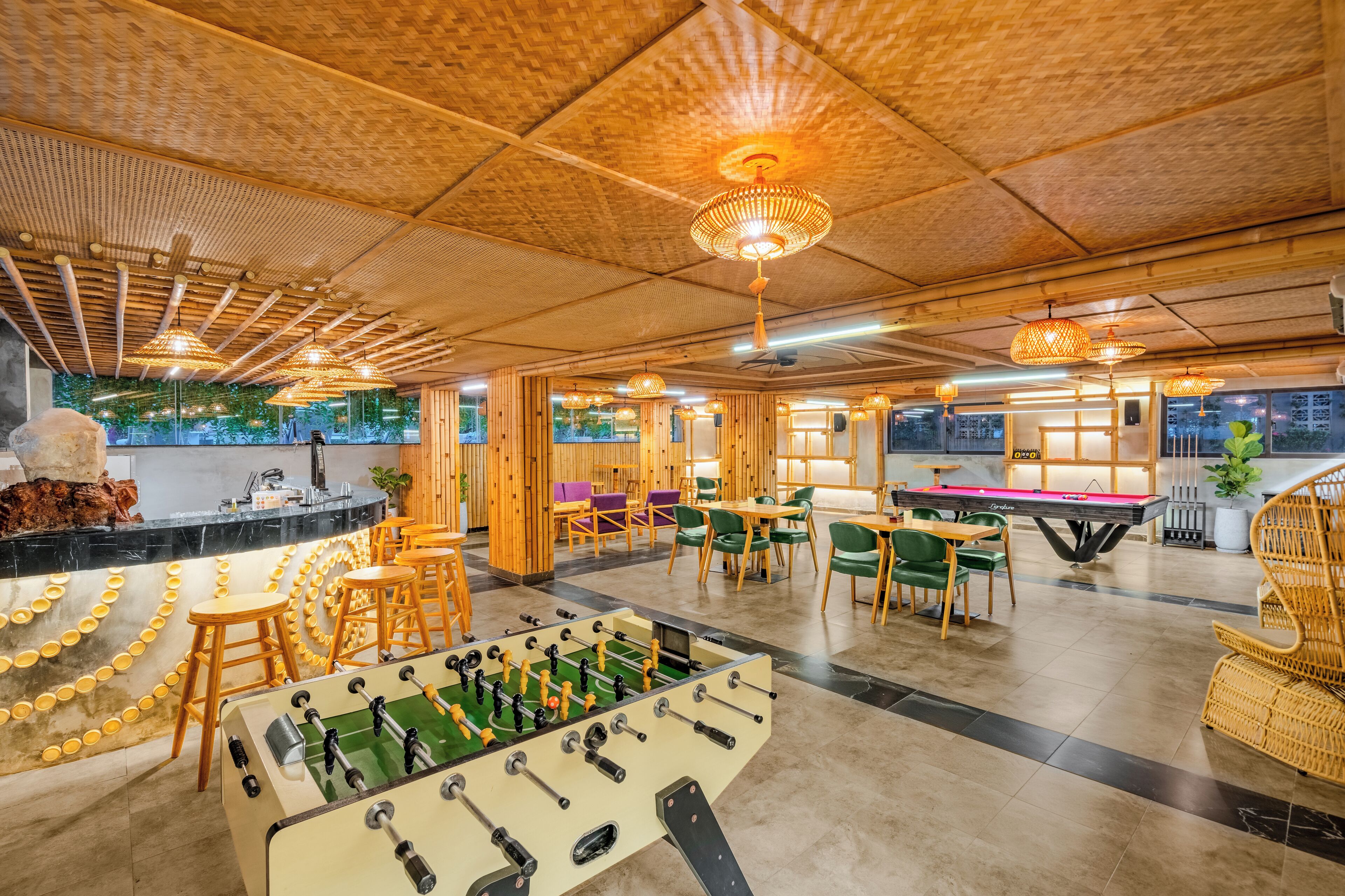 A spacious indoor area with a foosball table, multiple seating arrangements, and a pool table.