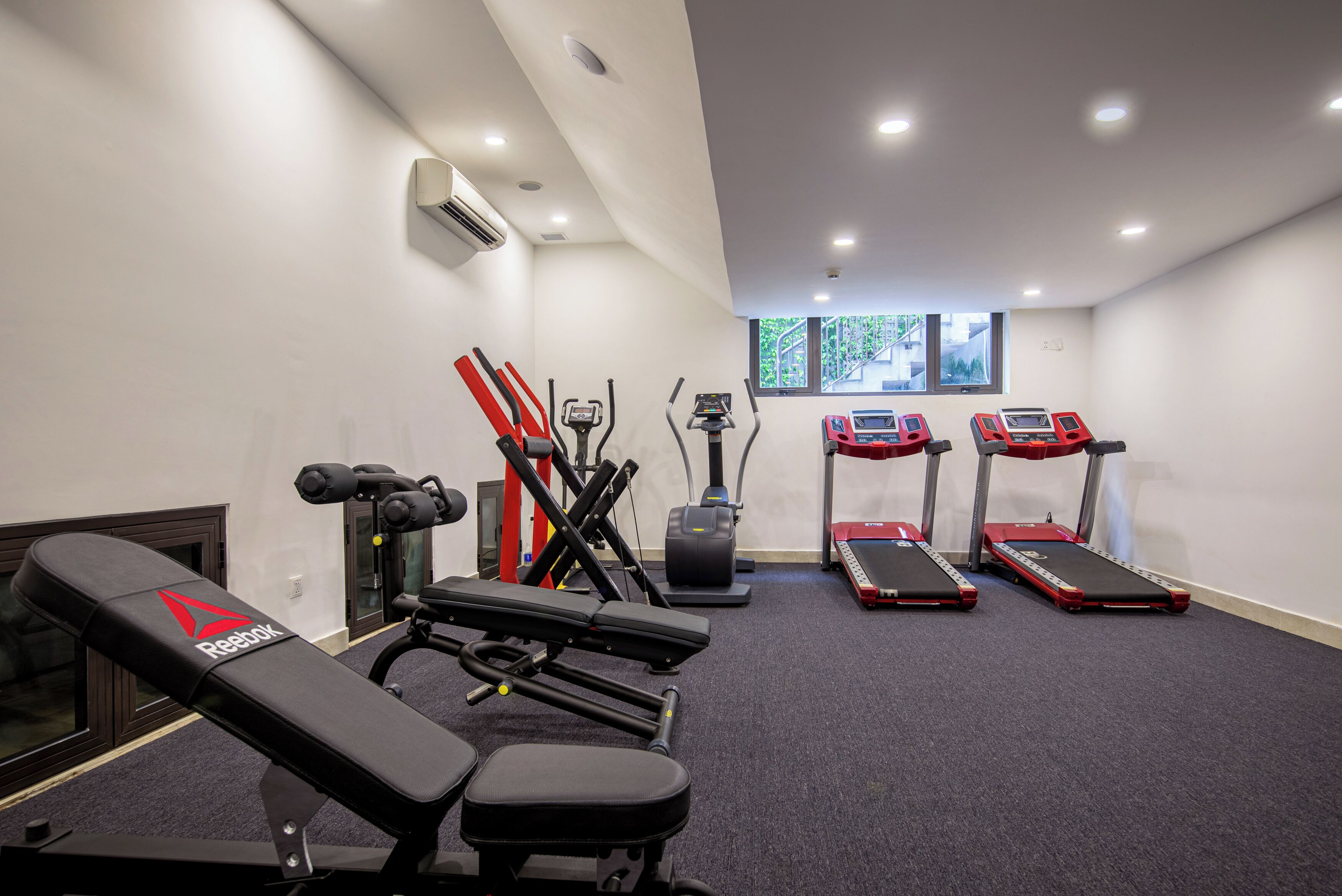 A modern gym with treadmills, a bench press, and a rowing machine.