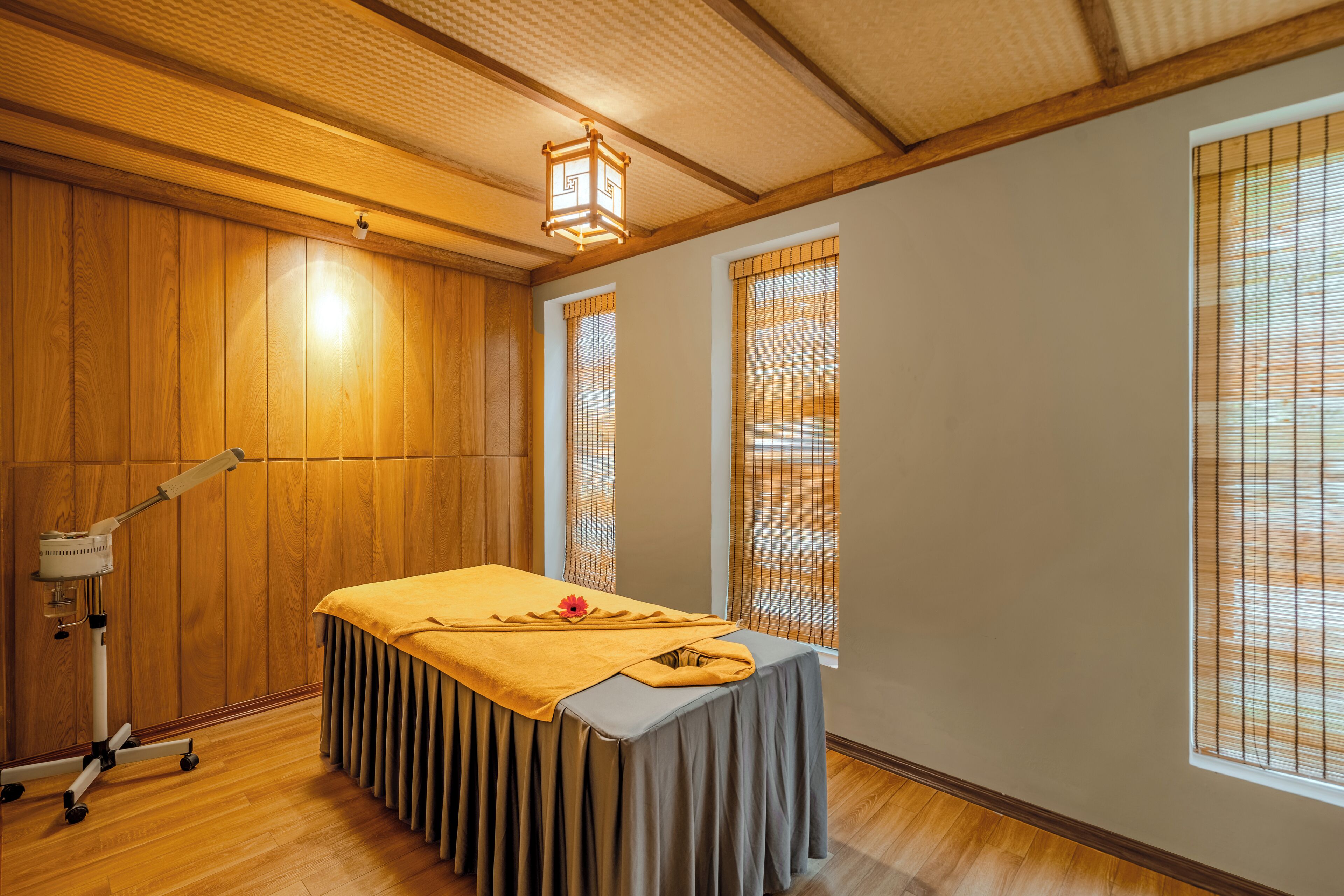Una habitación con paneles de madera, una mesa de masaje con una toalla amarilla y un sillón de masajes.