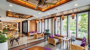 Eine geräumige Lobby mit Holzsitzmöbeln, großen Fenstern und einem Deckenventilator.