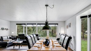 Un espace repas moderne avec une table en bois, des chaises en cuir noir et un luminaire suspendu.