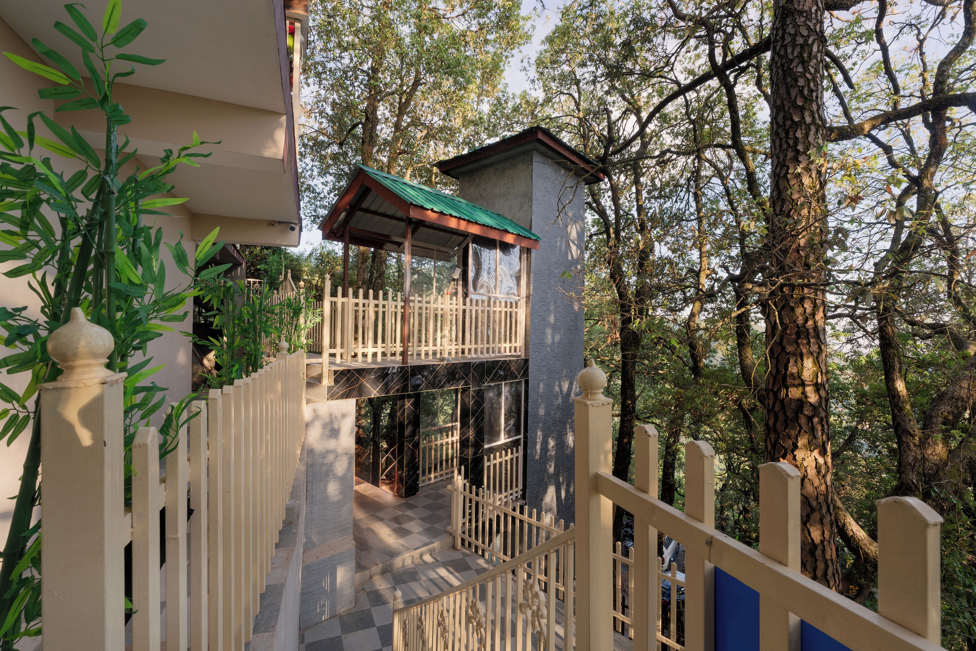 A staircase leading to a balcony with a checkered floor, surrounded by trees and a fence.