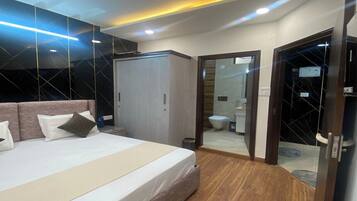 A modern bedroom with a large bed, a wardrobe, and a bathroom visible through an open door.