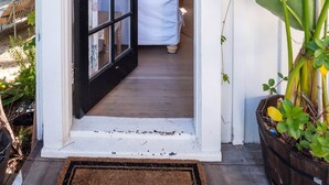 Una puerta con el número 15 en la pared, una puerta blanca y una habitación con una cama y una silla de mimbre.