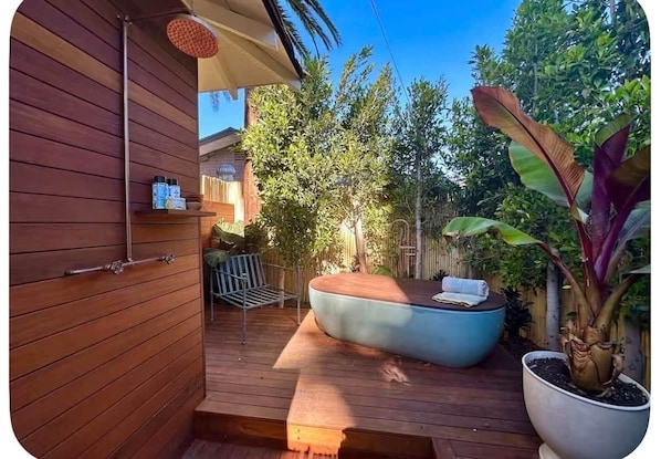 Una terraza de madera con una zona de estar integrada, una pequeña mesa y una planta en maceta.