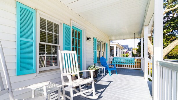 A covered porch with white railings, a rocking chair, and a table. - 3 Bdrm in Historic Downtown (Morehead City)