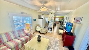 A cozy living room with a striped sofa, a coffee table, and a TV. - 3 Bdrm in Historic Downtown (Morehead City)