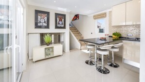 A modern kitchen with a central island, bar stools, and a staircase leading to an upper level.