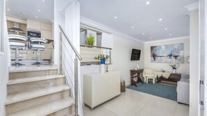 A modern apartment with a staircase, kitchen, living area, and a dining space.