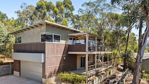 A two-story house with a garage, a covered outdoor area, and a garden.
