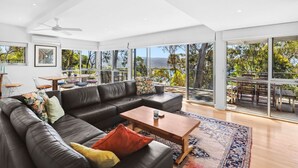A modern living room with a sectional sofa, a coffee table, and a large window offering a view of the outdoors.