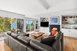 A modern living room with a fireplace, a large sofa, and a television.