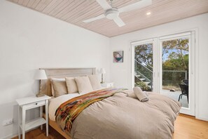 A bedroom with a bed, nightstands, a ceiling fan, and a view of an outdoor deck. - Coastwalk (Aireys Inlet)