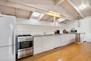 Eine moderne Küche mit weißen Schränken, einem Edelstahlherd und einem eingebauten Backofen.