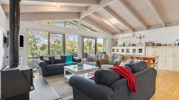 Un amplio salón con techo alto, chimenea y vistas al exterior.