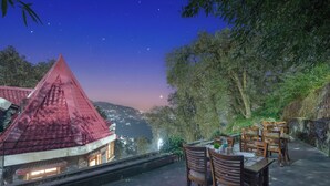 Un restaurante con terraza al aire libre que ofrece vistas panorámicas de una montaña y un lago, de noche.