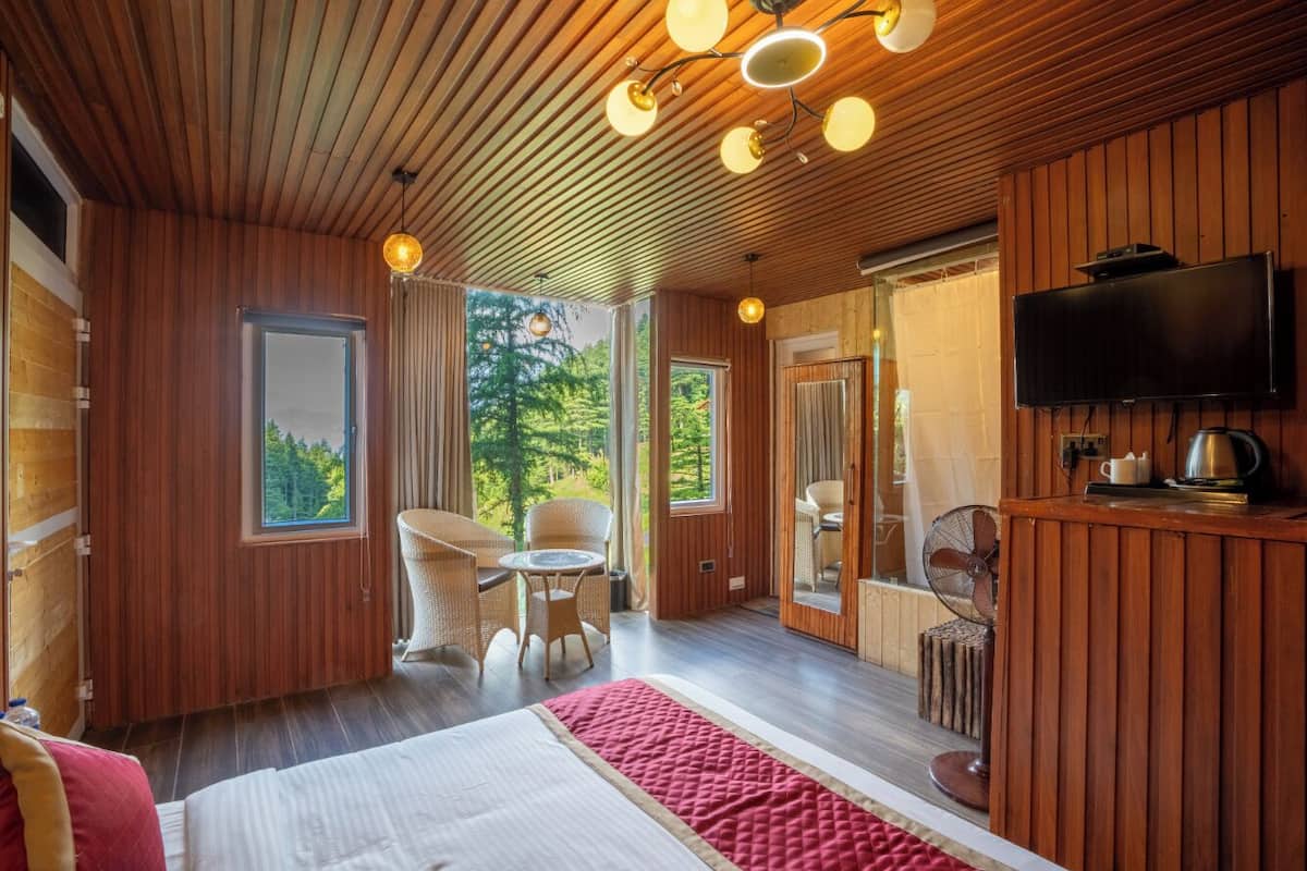 A modern room with wooden paneling, a bed, a TV, and a dining area with a table and chairs.