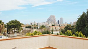 A cityscape with a prominent mountain-like structure in the background, surrounded by buildings and greenery.