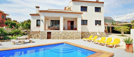 A two-story house with a swimming pool and outdoor seating.