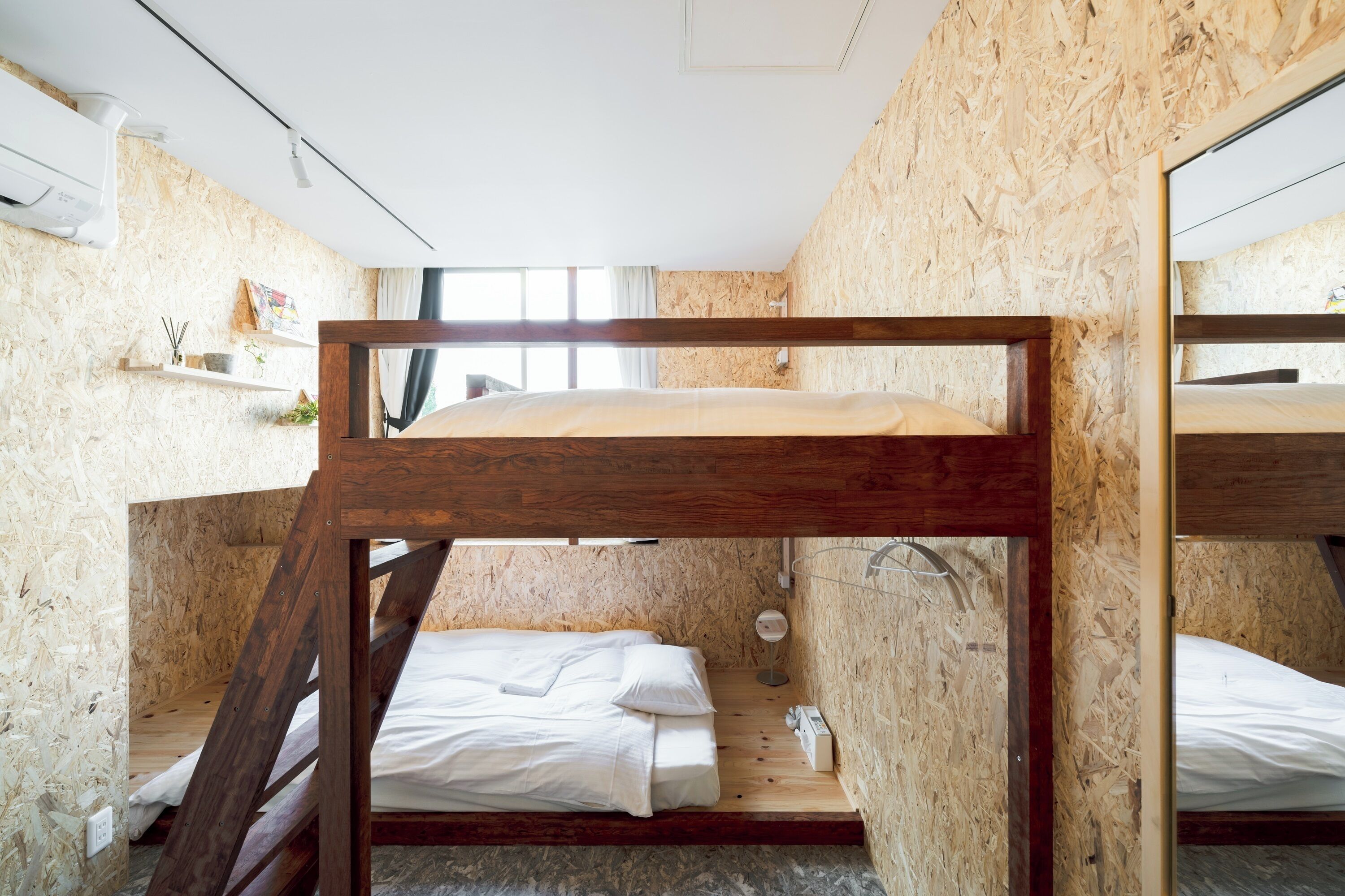 A bunk bed room with wooden walls and a small shelf with items.