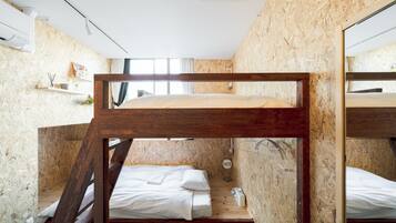 A bunk bed room with wooden walls and a small shelf with items.