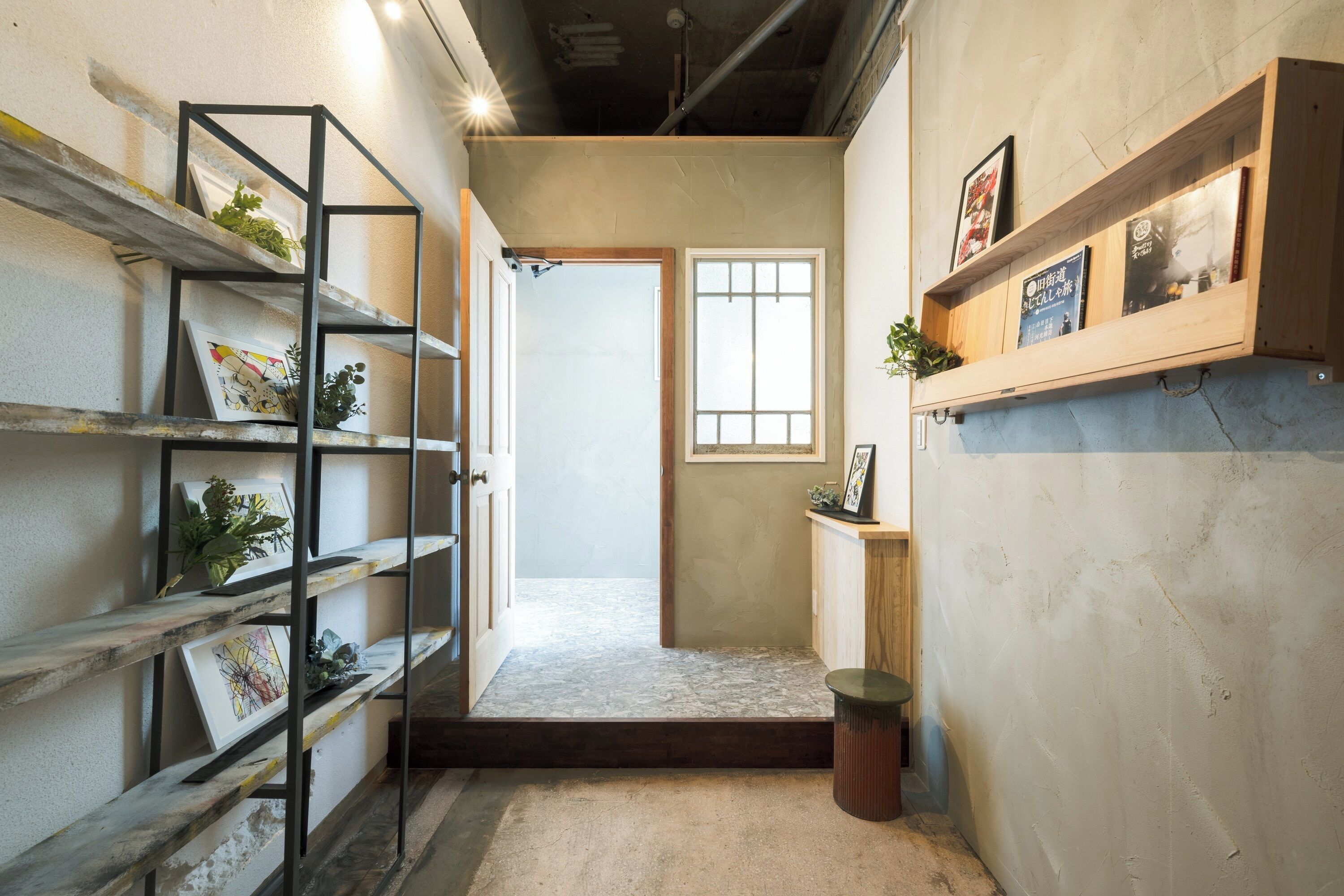 A hallway with a wooden door, a small window, and shelves with plants and books.